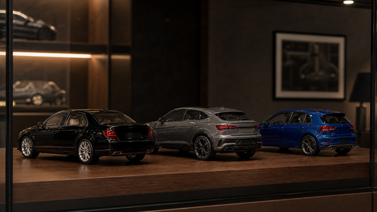 Three 1:18 collector model cars displayed in a cabinet